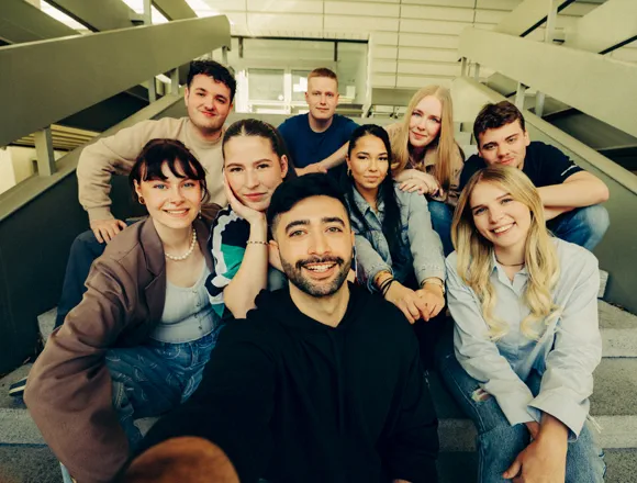IHK-Berlin-Azubiportal-Header-Gruppenbild Eine Gruppe junger Menschen sitzt auf einer Treppe